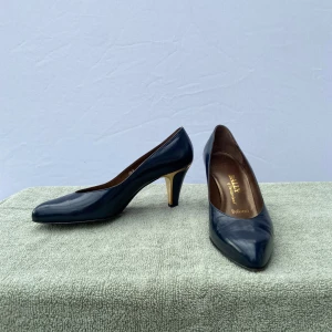 Bally Suisse Klackar - Elegant par högklackade skor från Bally Suisse i storlek 36.                                                                     Djup mörkblå färg som passar till det mesta. Skorna är i bra skick, använda men väl omhändertagna. Perfekt för både fest och mer uppklädda vardagsoutfits – en tidlös detalj i skogarderoben.