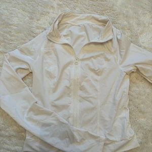 Vit kofta XS - Fräsch vit vindjacka från SHEIN i storlek XS. Jackan har hel dragkedja framtill, hög krage och långa ärmar. Materialet är lätt och syntetiskt, perfekt för blåsiga dagar. Snygg och enkel design som funkar till många olika stilar.