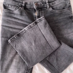Grå jeans från Bershka, storlek 34 - Snygga grå jeans från Bershka i storlek 34. Klassisk femficksmodell med utsvängda ben och normal passform. Jeansen har bälteshällor, knapp och dragkedja framtill. Perfekta till en chill vardagslook.