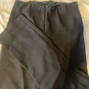 Svarta kostymbyxor från Vero Moda - Klassiska svarta kostymbyxor från Vero Moda i rak modell. Byxorna har en stilren look med dold dragkedja framtill och är perfekta för en clean och snygg outfit. Materialet känns mjukt och följsamt, vilket gör dem bekväma att bära hela dagen.