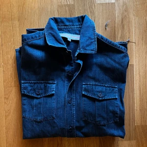  Jeansskjorta Orlebar Brown - Snygg mörkblå jeansskjorta från Orlebar Brown med klassisk krage och två bröstfickor med lock och knappar. Skjortan har raka linjer och är tillverkad i ett mjukt jeanstyg som ger en avslappnad men stilren look. Hör av dig vid funderingar! Mvh Carl