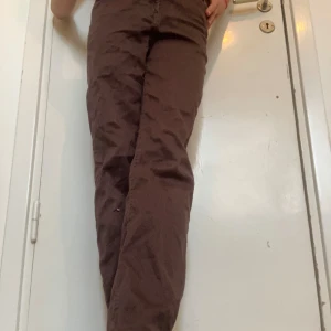 Bruna raka byxor från Lindex - Snygga bruna byxor från Lindex i rak modell med normal passform. Byxorna har klassisk femficksdesign, knapp och dragkedja framtill.  Perfekta för dig som gillar enkel och stilren look. Har en liten färgfläck på framsidan!