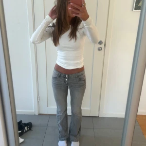 Lågmidjade gråa jeans - Säljer dessa superfina lågmidjade gråa jeans köpte för länge sen på Gina tricot!🥰  as cool knapp detalj på framsidan vid gylfen! de är slutsålda, i jättefint skick❤️ passar storlek XS