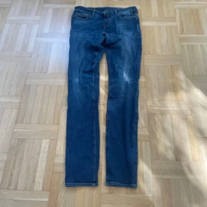 Blå Replay jeans LUZ, storlek 29 - Snygga blå jeans från Replay i modellen LUZ. Klassisk femficksdesign, raka ben och normal passform. Jeansen har en mörkblå tvätt med lätt slitna detaljer och är tillverkade i mjukt denimtyg. Perfekta för en avslappnad och stilren look.