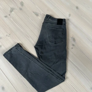 Replay Anbass grå jeans herr 34 - Snygga Replay Anbass jeans i mörkgrå tvätt med klassisk femficksdesign och raka ben. Jeansen har diskreta sömmar och svart patch bak i midjan. Perfekta för dig som gillar stilrena och bekväma jeans med modern passform. Säljer för jag tyckte dem var för tighta. Hör av er vid frågor!