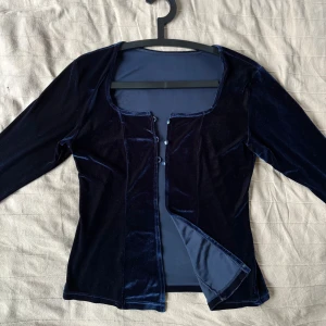 Mörkblå sammetstopp med knappar - Snygg mörkblå topp i mjuk sammet med långa ärmar. Framsidan har dekorativa små knappar som ger en elegant touch. Så snygg till typ en lång svart klänning och massa annat!  