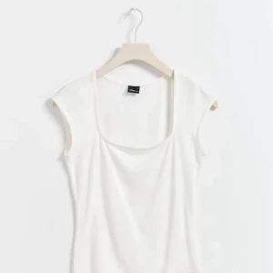 Gina soft touch - Fräsch vit linnetopp från Monki med snygg fyrkantig halsringning och breda axelband. Toppen är ärmlös och har en clean, enkel design som är lätt att matcha med allt. Perfekt för varma dagar och chill stil.