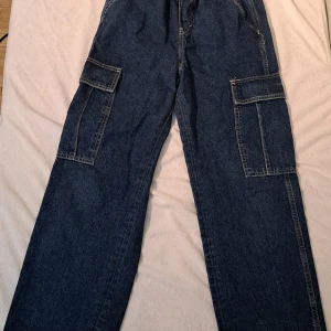 Baggy cargoish jeans - Baggy blåa jeans, med elastisk midja och många fickor. Köptes på hm, står inte exact storlek men skulle gissa S eller XS. 