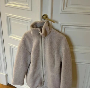 Beige teddyjacka - Mysig beige teddyjacka med hög krage och hel dragkedja framtill. Jackan har en rak passform och en bröstficka. (Inte mina bilder) säljer för att den inte kommer till användning 💕Tveka inte att skriva om du har frågor 😊