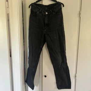 Svarta raka jeans - Säljer ett par svarta jeans med raka ben och klassisk femficksdesign, lite baggy stil. Jeansen har hög midja och silverfärgad knapp framtill. Perfekta till vardags för en stilren look. Mina favoritjeans under högstadiet. 100% bomull, så ingen stretch.