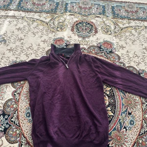 Lila stickad polotröja med dragkedja från Dressmann - Säljer en lila stickad polotröja från Dressmann i storlek S. Tröjan har lång ärm, hög krage och dragkedja framtill. Perfekt för kyligare dagar och enkel att matcha med jeans eller chinos.