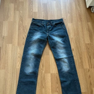 Blå jeansbyxor från G-Star RAW - Säljer ett par klassiska blå jeansbyxor från G-Star RAW med raka ben och slitningar framtill. Jeansen har fem fickor, bälteshällor och tydliga kontrastsömmar. Perfekta för dig som gillar en tidlös och avslappnad stil.