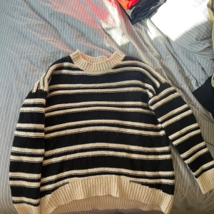 Stickad tröja, svart/gräddvit - Mysig stickad tröja i svart och beige med breda horisontella ränder. Tröjan har rund halsringning och ribbade muddar vid ärmslut och nederkant. Perfekt för kyligare dagar och enkel att matcha med jeans eller kjol. Passar strlk S! Kan mötas i Göteborg:)