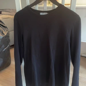 Svart långärmad tröja från Weekday - En stilren svart långärmad tröja från Weekday. Tröjan har rund halsringning och är tillverkad i ett mjukt bomullsmaterial. Perfekt basplagg att ha i garderoben.