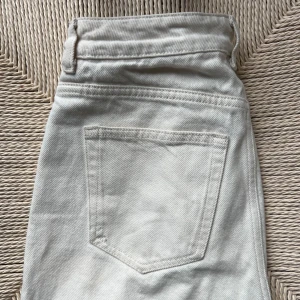 Vita jeansbyxor raka Bik Bok - Säljer ett par vita jeansbyxor från bik bok med klassisk femficksdesign och raka ben. Byxorna har hög midja och stängs med knappar och dragkedja. Se bild för defekter nertill på byxan, inget som syns när man bär dem. 