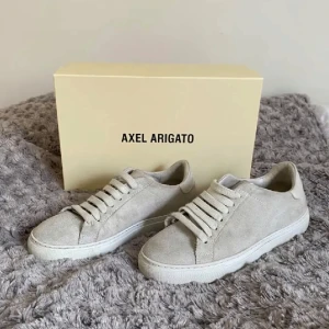Axel arigato - Snygga beige sneakers från Axel Arigato i modellen Clean 90 C90 Version Suede. Skorna har en stilren design med snörning och är tillverkade i mocka med en vit sula. Storlek 35, passar 36 också. Nypris 2690kr