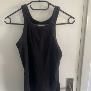 Svart ribbad linnetopp från Zara - Säljer en svart ribbad linnetopp från Zara. Toppen har en tight passform och är ärmlös med breda axelband. Perfekt att styla till olika outfits och funkar året runt.