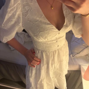 Vit kortklänning med puffärmar och v-ringning - Superfin vit kortklänning med v-ringad hals och puffiga kortärmar. Klänningen har markerad midja och ett subtilt blommigt mönster i tyget. Perfekt för sommarens alla tillfällen! Lappen sitter inte kvar men klänningen är från Showpo och skulle uppskattas till storlek S