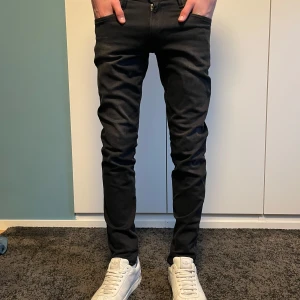 Svarta slim jeansbyxor - Säljer ett par svarta slim jeansbyxor med klassisk femficksdesign och dragkedja. Byxorna har en smal passform och normal midja, perfekta till sneakers eller boots. Snygga och stilrena för en modern look.