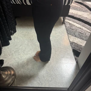Svarta straight jeansbyxor - Säljer ett par svarta jeansbyxor med straight passform och hög midja. Klassisk femficksmodell med dragkedja och knapp framtill. Perfekta till en enkel t-shirt eller stickad tröja. Från bikbok 