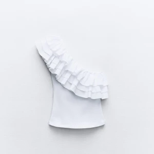 Vit one shoulder topp med volang från Zara - Säljer en vit one shoulder topp från Zara med stora volanger längs axeln. Använd ett fåtal gånger 