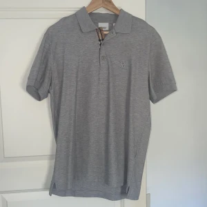 pikétröja från Burberry - Grå pikétröja från Burberry, använd 2-3 gånger säljs pågrund av att den är för liten.