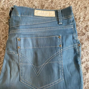 Blå jeansbyxor från GABBA - Snygga blå jeansbyxor från GABBA med raka ben och klassiska kontrastsömmar. Byxorna har knappgylf och femficksdesign. Perfekta för dig som gillar en tidlös och stilren look. Skriv gärna för fler bilder eller funderingar.