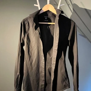 Svart slim fit skjorta från Smog - Säljer en svart skjorta från Smog i slim fit-modell. Skjortan har långa ärmar och knäppning framtill. Perfekt för dig som gillar en stilren och enkel look.