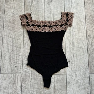 Svart body med spets från Intimissimi - Säljer en svart body från Intimissimi med bred beige spets upptill och offshoulder-modell. Perfekt för dig som vill ha en elegant och feminin topp med fina spetsdetaljer. Den säljs inte lägre på intimissimis hemsida. 