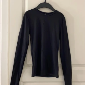 Svart långärmad topp från H&M - En enkel och stilren svart långärmad topp från H&M. Modellen är tight och har rund halsringning. Perfekt att styla med jeans eller kjol för en clean look. Den är tajta.