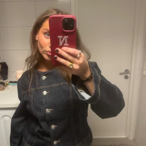 Mörkblå jeansjacka med vida ärmar - Säljer en mörkblå jeansjacka med markerade sömmar och stora, vida ärmar. Jackan har knappar framtill och en cool, lite oversized passform. Perfekt för dig som vill sticka ut med en unik denimlook.