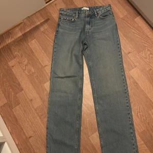 Blå raka low waist jeans från Gina tricot  - Klassiska blå jeans från gina tricot med raka ben och femficksmodell. Jeansen har normal passform och låg midja perfekt för en avslappnad stil. Tidlös design med guldfärgade nitar vid fickorna.