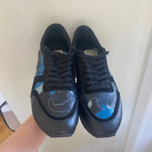 Valentino Rockrunners - Säljer ett par Valentino Rockrunner sneakers med svart bas och blått camouflage-mönster. | 8,5/10 skick | använda men har varit på reperation och kan synas lite grann på framsidan av skon | Box medföljer samt extra skosnören. | Om ni funderar över något så är det bara o skriva!