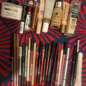 Samling av olika sminkprodukter (priset kan diskuteras vid snabb affär)  - En samling av olika sminkprodukter inklusive läppstift, läppglans, concealer och highlighter. Märken som Revolution, NYX och Lene Østergaard finns representerade. Färgerna varierar från neutrala toner till djärva röda och rosa nyanser. Perfekt för att skapa en komplett sminklook.