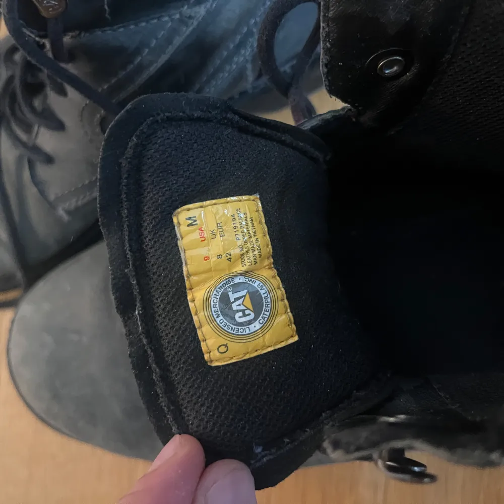 Säljer ett par robusta svarta boots från Caterpillar. Skorna har snörning och är tillverkade i slitstarkt material, perfekt för utomhusaktiviteter. De har en rund tå och en stabil sula för extra komfort.. Kengät.