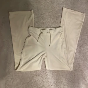 Beige mjukisbyxor från Gina Tricot - Säljer ett par bekväma beige mjukisbyxor från Gina Tricot. Byxorna har en loose passform och har snörning i midjan för justerbar passform. Perfekta för en avslappnad stil.