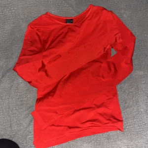 Röd långärmad tröja - Säljer en stilren röd långärmad tröja. Perfekt för att lägga till en färgklick i din garderob. Tröjan har en enkel design och är gjord i ett mjukt material för extra komfort.