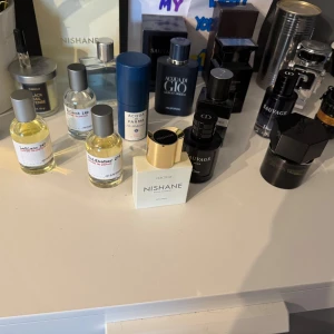 Parfymkollektion med olika märken - En samling av exklusiva parfymer från olika märken som Nishane, Acqua di Parma och Dior. Flaskorna varierar i form och storlek, med eleganta och moderna designinslag. Perfekt för den som vill ha en varierad doftgarderob.