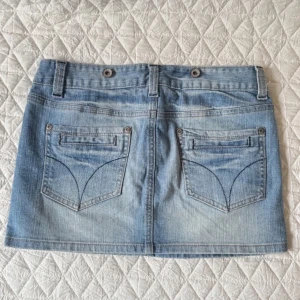 Low waist jeanskjol - Snygg blå jeanskjol från Pimkie med klassisk femficksdesign och knappgylf. Midjemått 38cm Längd 29cm. 