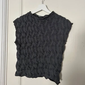 Svart topp från Gina tricot  - Snygg grå topp från Gina tricot med korta ärmar. 