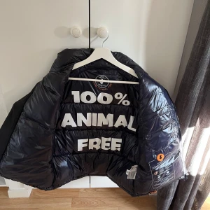 Marinblå save the duck väst  - Snygg marinblå dunväst med glansig yta och dragkedja framtill. Västen är 100% animal free och har en modern look. Perfekt för att hålla värmen utan att kompromissa med stilen.