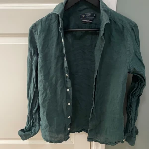 Grön linneskjorta från Riley - Snygg grön skjorta från Riley i linne. Skjortan har långa ärmar och knappar framtill. Perfekt för en stilren och avslappnad look.