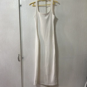 Vit ribbad klänning från Shein - Säljer en stilren vit ribbad klänning från Shein. Klänningen är ärmlös och har en smickrande passform som sträcker sig till vaderna. Perfekt för en minimalistisk look.