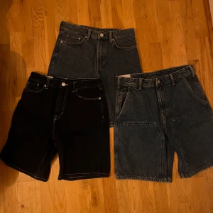 Tre par jeansshorts i olika färger - Säljer tre par jeansshorts i olika färger. Ett par är svarta, ett par är mörkblå och det tredje paret är ljusblå. Alla har klassisk femficksdesign och knappgylf. Perfekta för en avslappnad stil. Alla 3 par för 250kr