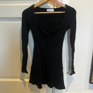 Svart ribbad klänning från Berskha - Snygg svart ribbad klänning med långa ärmar och knytning framtill. Aldrig använd. 