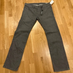 Grå jeansbyxor från Diesel - Snygga grå jeansbyxor från Diesel i modellen Safado. De är slim-straight och är helt nya. Helt nya med prislapp och allt kvar!                           Midjemått: 46 cm rakt över, innerbenslängd: 82 cm, lårbredd rakt över: 28 cm, ankelbredd rakt över: 21 cm.                                                                     W: 32 L: 32