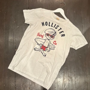 Hollister T-Shirt - Denna riktigt snygga t-shirt från Hollister är knappt använd och har inga defekter . Storleken är S men jag skulle säga att den sitter lite större. Modellen på bilden är 188 cm och väger 70 kg. Om ni har några frågor är det bara att skriva!          /T-Arkivet 👕😁