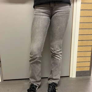 Grå jeans - Snygga grå jeansbyxor med en tight passform och bootcut-stil. Byxorna har en klassisk design med fem fickor och knappgylf. Perfekta för en stilren look.