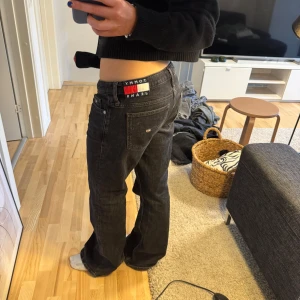 Svarta jeans från Tommy Jeans, low rise bootcut - Snygga svarta jeans från Tommy Jeans med låg midja och bootcut-stil. Perfekta för en avslappnad look. Sophie low rise bootcut' modellen. Klassisk design med fem fickor och knappgylf.