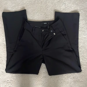 Svarta kostymbyxor från BikBok - Snygga svarta kostymbyxor från BikBok med dragkedja och knapp framtill. Byxorna har en klassisk design med raka ben och fickor i sidan. Säljer dem för att dem inte passar längre💕